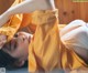 A woman laying on the floor under a yellow sheet.