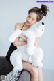 A woman sitting on a couch holding a white teddy bear.