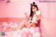 A woman sitting in a bathtub filled with pink and white balls.