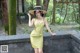 A woman in a yellow dress and a straw hat posing for a picture.