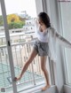 A woman standing on a balcony looking out a window.