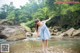 A woman in a blue and white dress standing in a river.