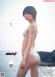 A woman in a white bikini standing on a beach.