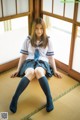 A woman in a school uniform sitting on the floor.