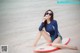 A woman sitting on a surfboard on the beach.