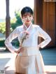 A woman in a white and beige hanbok poses for a picture.