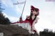 A woman in a red and white dress sitting on a rock.