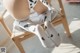 A baby sitting on a wooden chair wearing white socks with black spots.