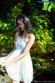 A woman in a white dress standing in the woods.