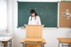 A woman standing at a podium in front of a blackboard.