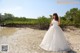 A woman in a wedding dress standing on a beach.