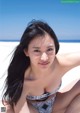 A woman in a bikini sitting on the beach.