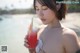 A woman holding a glass of watermelon juice on the beach.